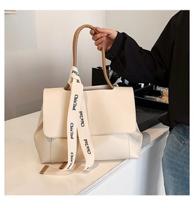 Detailed macro view of the beige faux leather texture and branded fabric strap on handbag