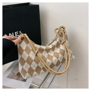 Detail of checkered canvas underarm bag with metal ring buckles and brown shoulder strap