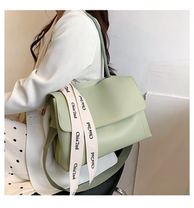 Detail of light green minimalist shoulder bag with stylish branded fabric strap tag