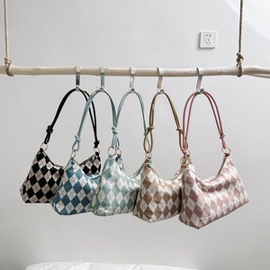 Five assorted argyle pattern shoulder bags in classic colors hanging on a wooden branch