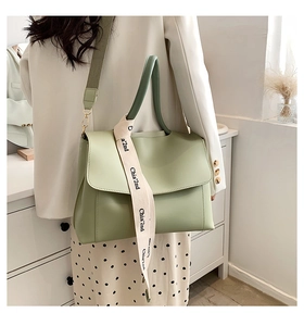 Detail of light green PU leather tote with a stylish branded canvas shoulder strap