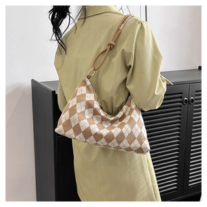 Detail of checkered hobo bag with brown leather strap and golden ring hardware