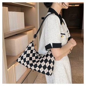 Detail view of the black and white checkered pattern and crescent shape of this shoulder bag