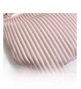 Detail presentation of the pink ruched leather texture and vertical stitching on the bag