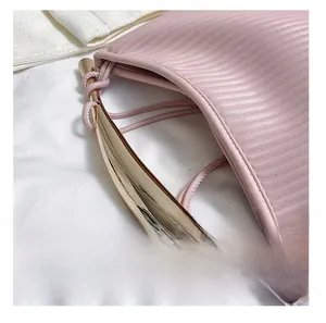 Detailed view of pink pleated handbag featuring elegant golden streamlined metal handle