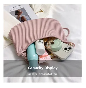 Detail showing internal capacity of the pink pleated bag with phone and cosmetics