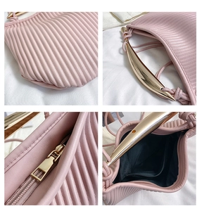 Detailed view of pink pleated handbag featuring crescent golden metal handle and inner pocket