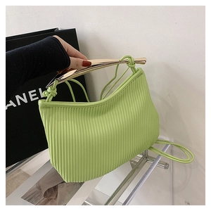 Detail of lime green pleated bag with golden round metal handle and fine PU texture