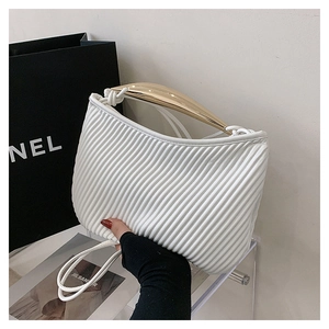Detail of white pleated handbag featuring a distinctive gold curved metal top handle