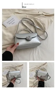 Detail of silver crossbody bag with beaded handle and metallic disc lock closure