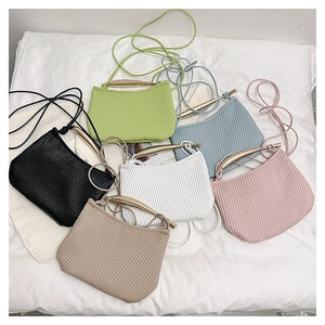 Flat lay of small pleated square bags in six colors with gold metal handles and thin straps
