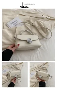 Detail of white mini crossbody bag with pearl handle and golden spiral metal lock closure