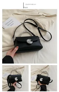 Detail view of black mini crossbody bag featuring pearl handle and metal clasp buckle