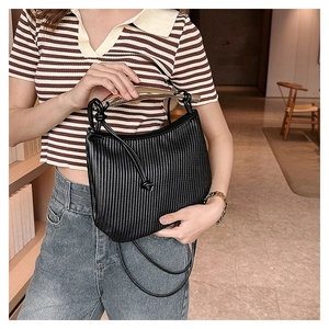 Detail of black pleated crossbody bag with a curved gold metal handle and leather knot