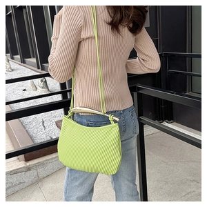 Close-up of lime green pleated shoulder bag with gold hardware and slim strap detail