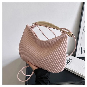 Detail of pink pleated handbag with modern gold metal handle and slim shoulder strap