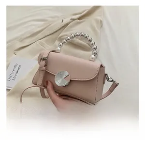 Pink leather handbag detail featuring gradient pearl handle and silver spiral disk lock