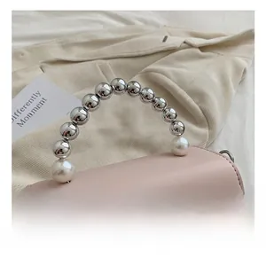 Detail of light pink mini bag with pearl beaded handle and silver metal lock closure