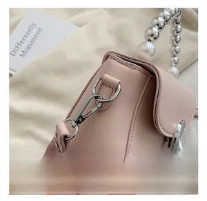 Detail of pink mini bag featuring silver metal hook and beaded pearl handle