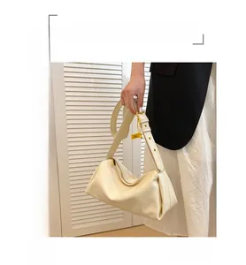 Detail of creamy white pleated leather shoulder bag with adjustable gold buckle strap