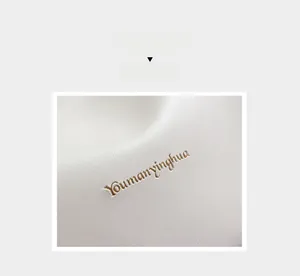 Detail of white lychee grain leather handbag featuring elegant gold embossed logo