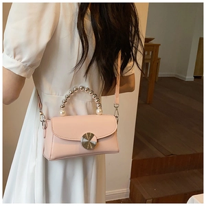 Detail of pink mini square bag with pearl handle and metal lock on white dress