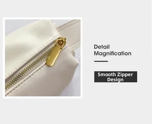 Detailed close-up of the smooth golden metal zipper on a cream white leather shoulder bag