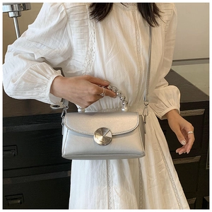 Close-up of silver mini crossbody bag featuring a pearl handle and circular metal lock