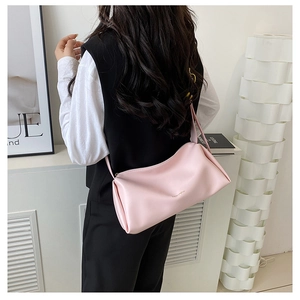 Detail of soft pink faux leather underarm bag with gold logo on a female model