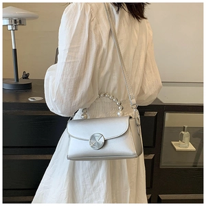 Detail of silver mini square bag with pearl handle and metallic lock on a model