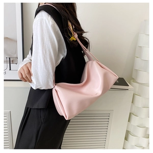 Detail of pink cylindrical shoulder bag featuring soft pleated leather and a gold zipper
