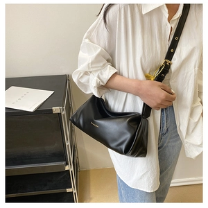 Detail of a black leather underarm bag with gold logo and adjustable shoulder strap