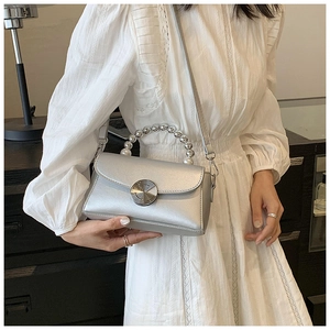 Detail of silver mini crossbody bag featuring pearl beaded handle and metallic clasp