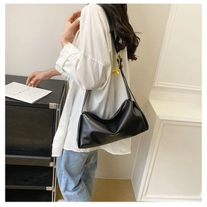 Close-up of a minimalist black underarm bag with pleated design and gold logo