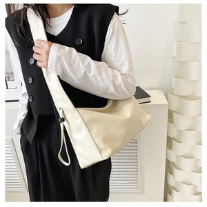 Detail view of cream oversized crossbody bag with wide shoulder strap and side drawstring