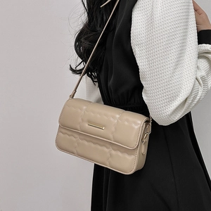 Minimalistische beige gesteppte Umhängetasche mit Goldschnalle am Model im Kleid
