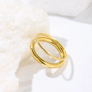 Polished golden minimalist chain rings displayed on white natural crystal stone texture