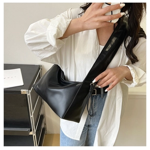 Minimalist black matte hobo bag with wide shoulder strap worn by model in studio