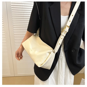 Detail of creamy beige leather handbag with gold metal hardware and adjustable strap