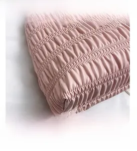 Macro detail of soft pink pleated leather handbag showing fine texture and sewing craft