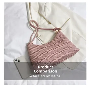 Close-up of pink pleated baguette bag on white blazer showing texture and metal buckle