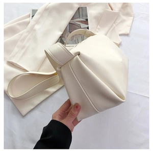 Detail of cream minimalist handbag showing side contrast stitching and soft faux leather texture
