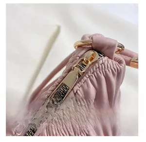 Macro shot of smooth gold zipper and wrinkled pink leather texture on tote bag