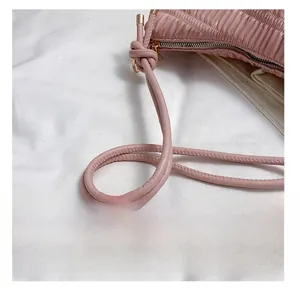 Close-up of pink pleated leather bag with knotted handle detail and gold metallic zipper