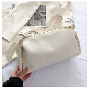 Detail of adjustable leather strap with gold buckles on a chic cream underarm bag