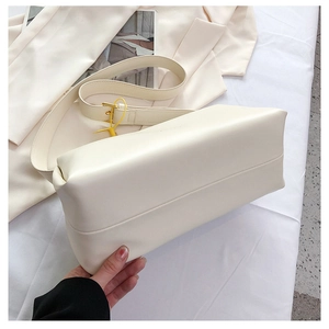 Close-up of cream rectangular leather shoulder bag with gold hardware and logo detail