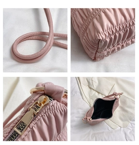Detail view of pink pleated handbag showing gold hardware, texture, and internal pockets