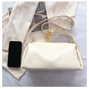 Detail of a minimalist cream leather underarm bag with gold logo and adjustable shoulder strap