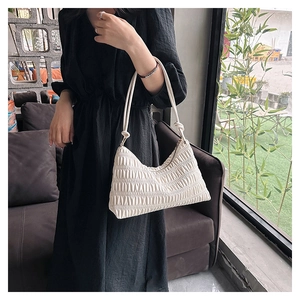 Elegant off-white pleated hobo bag worn by model, featuring unique horizontal textures