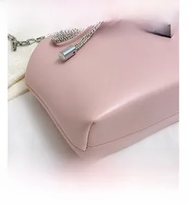 Close-up of pink shell bag with shimmering rhinestone bow and silver chain strap
